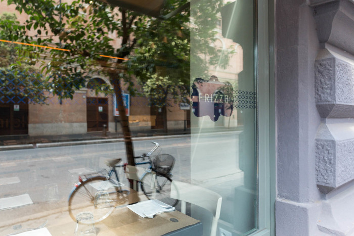 Fotografia d'interni: bicicletta riflessa nella vetrina di Frizzo, ristorante a Roma
